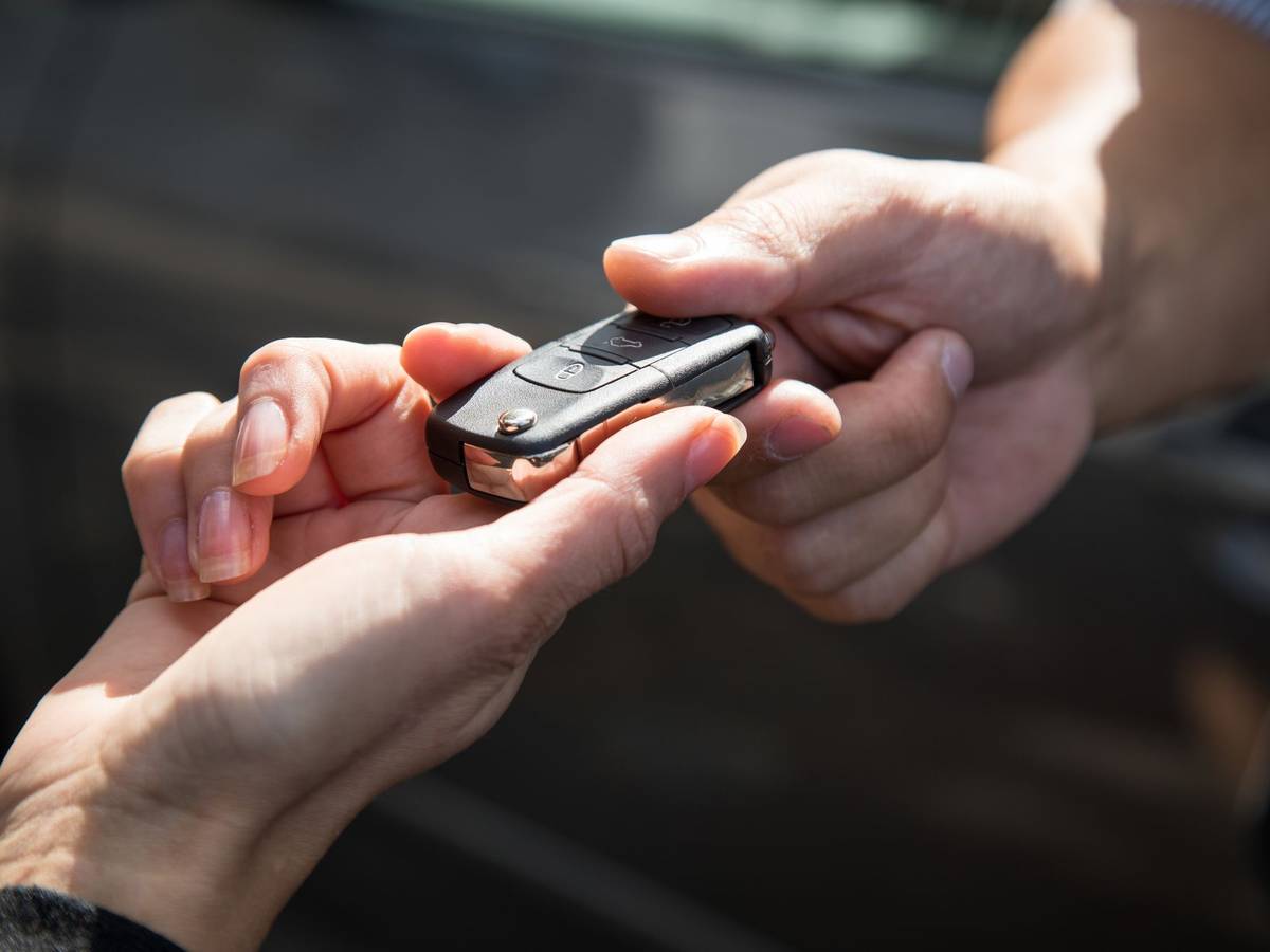 Eine Frau übergibt einen Autoschlüssel