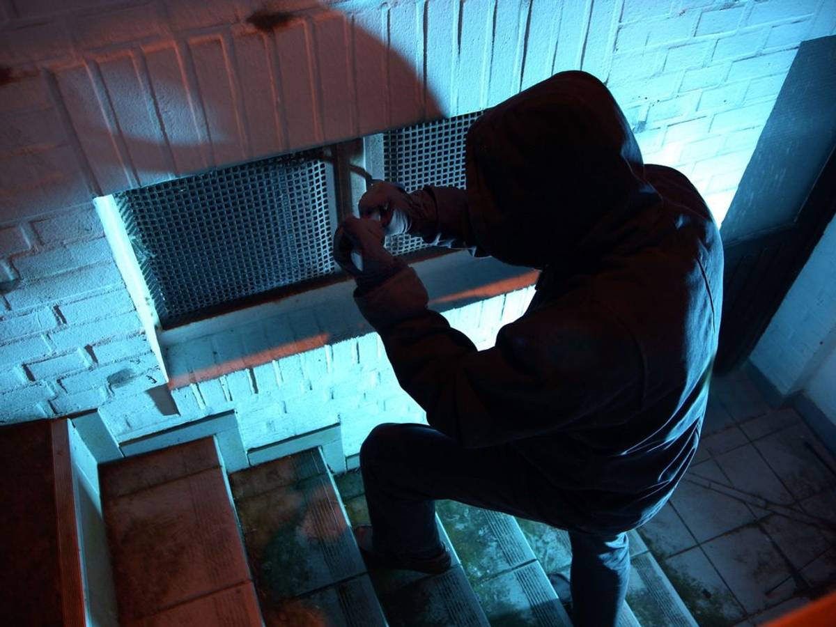 Einbrecher steigt in ein Haus ein.