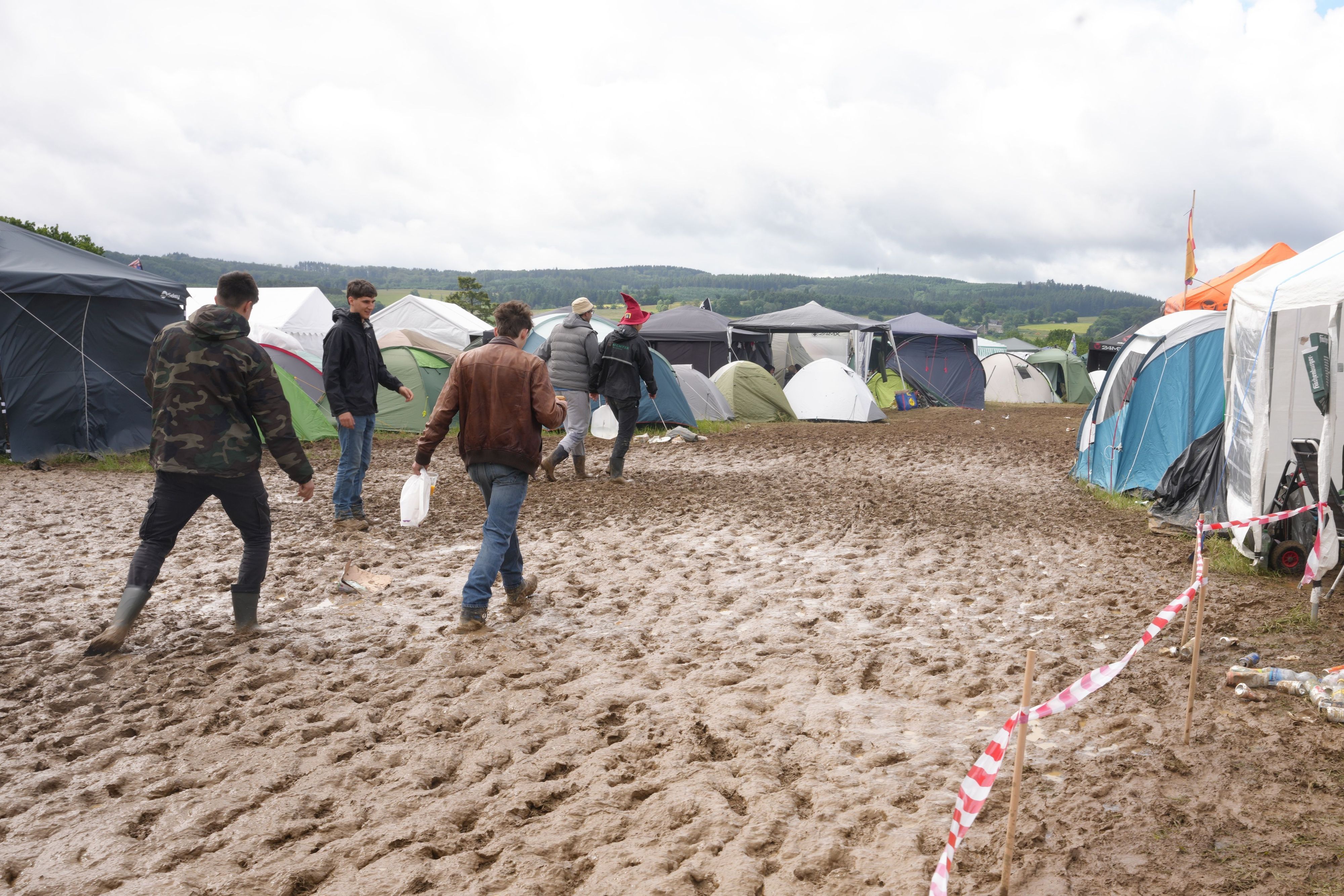 Rock am Ring: Camper gehen durch den Schlamm.