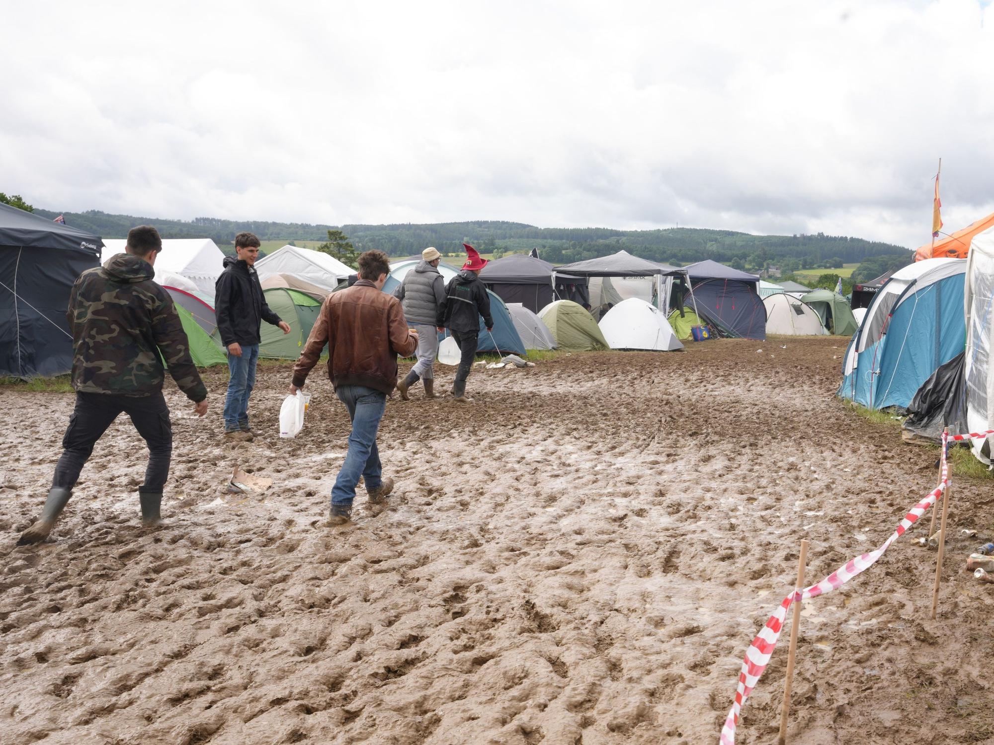 Rock am Ring: Camper gehen durch den Schlamm.
