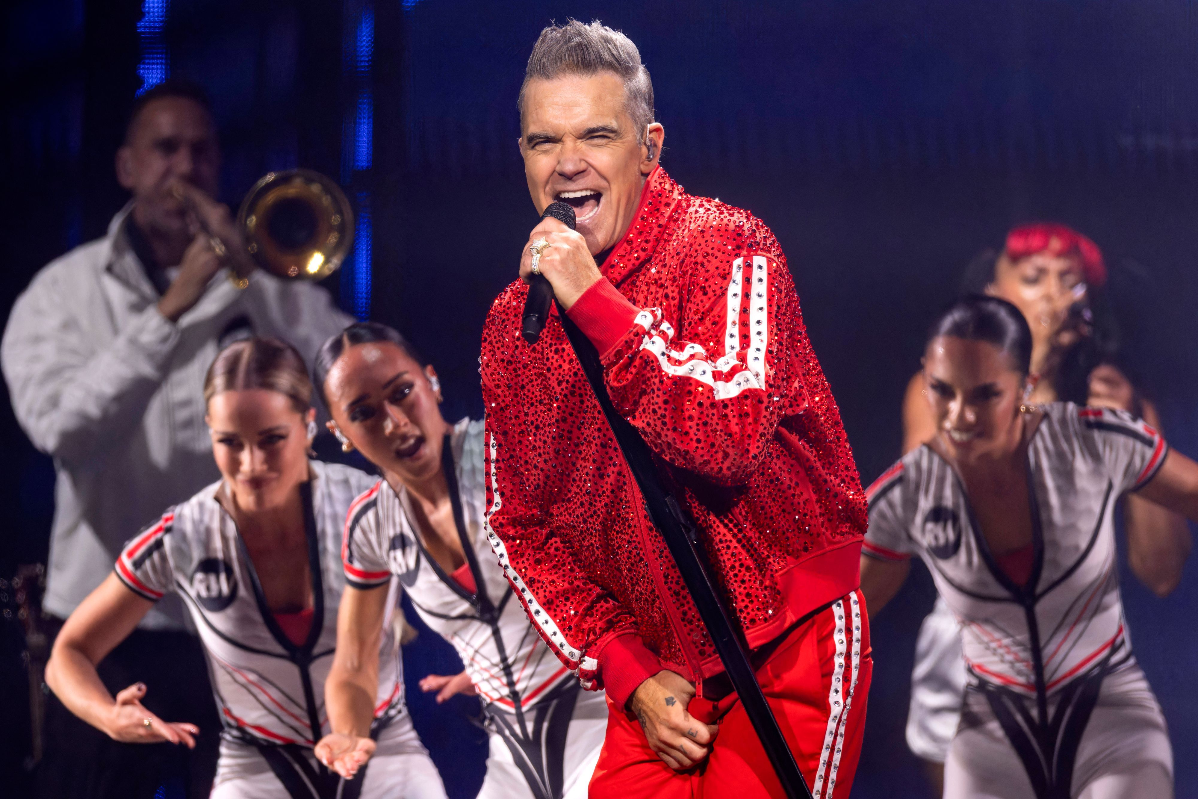 Robbie Williams singt auf einer Bühne.