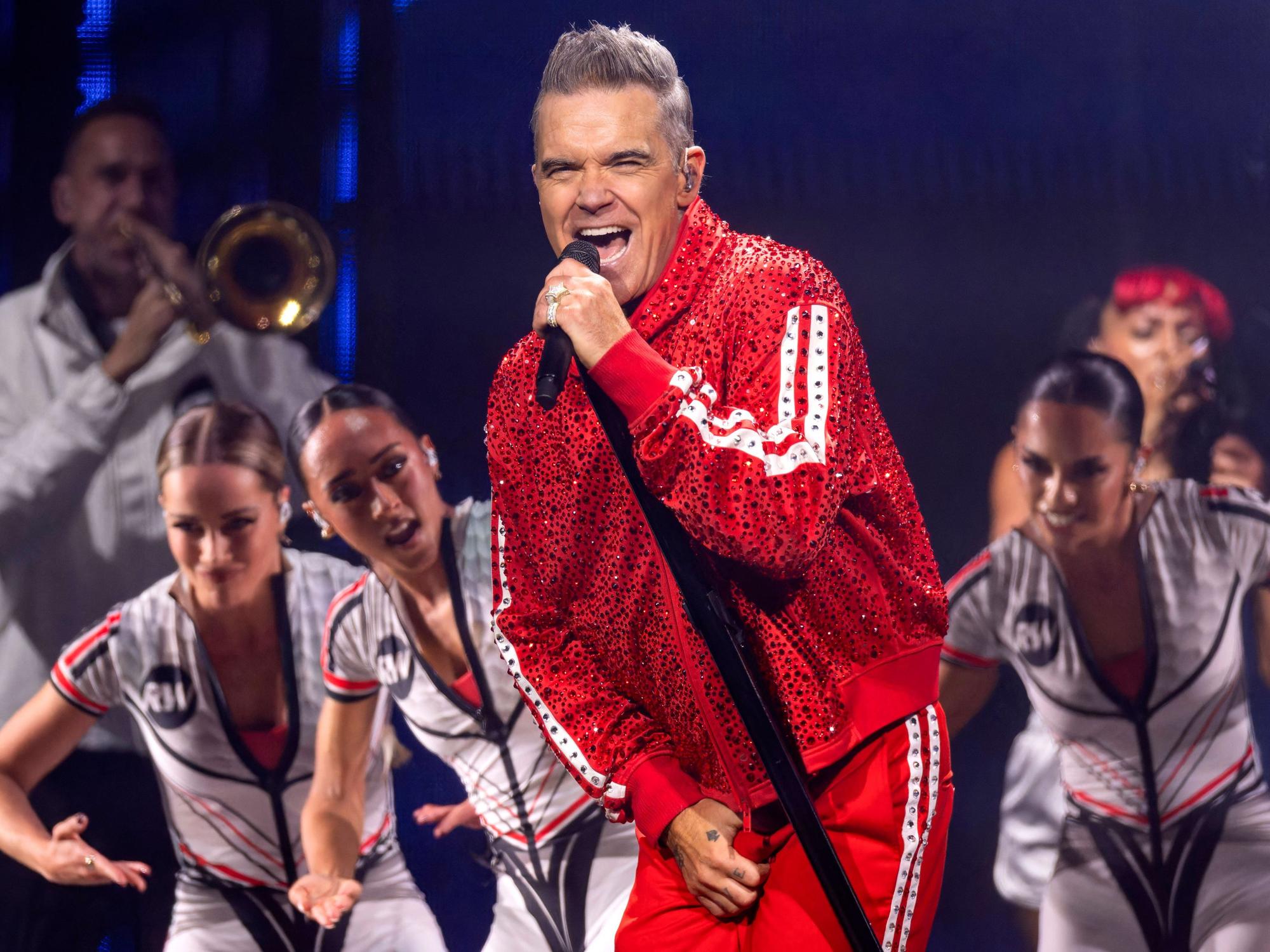 Robbie Williams singt auf einer Bühne.