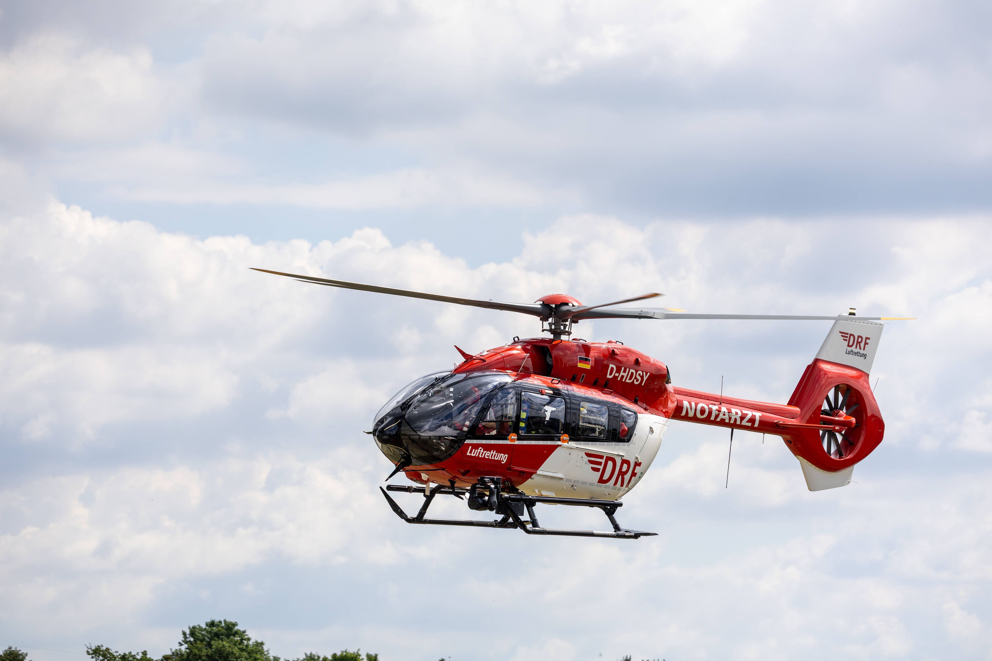 Rettungshubschrauber fliegt durch bewölkten Himmel