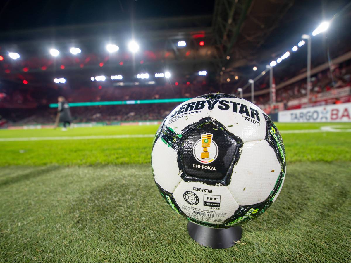 Ein Derbystar-Ball des DFB-Pokals liegt auf dem Rasen. Im Hintergrund sieht man das Stadion von Fortuna Düsseldorf.