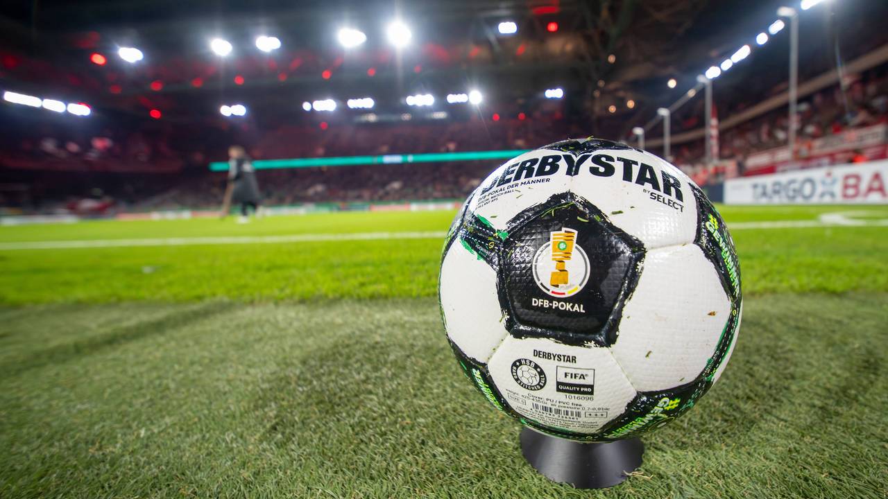 Ein Derbystar-Ball des DFB-Pokals liegt auf dem Rasen. Im Hintergrund sieht man das Stadion von Fortuna Düsseldorf.