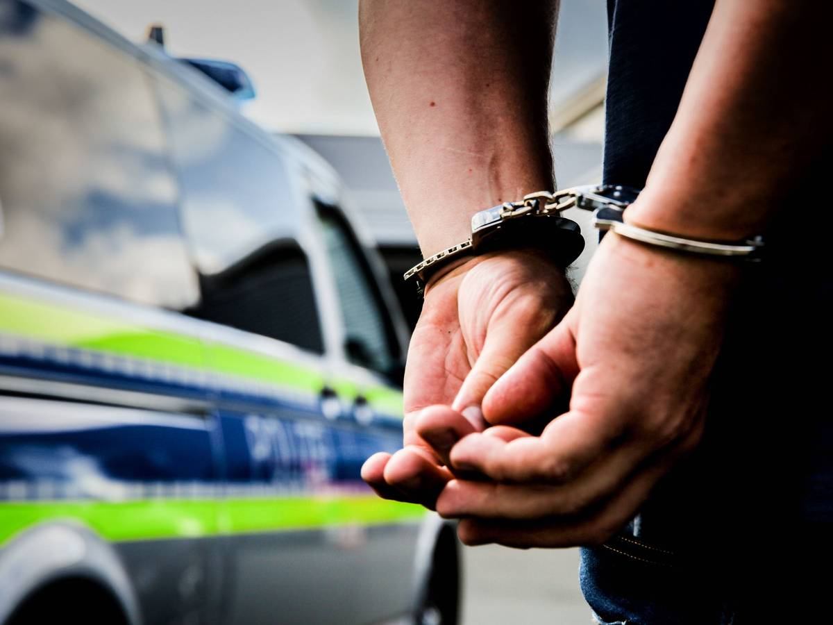 Mann in Handschellen vor Polizeiwagen