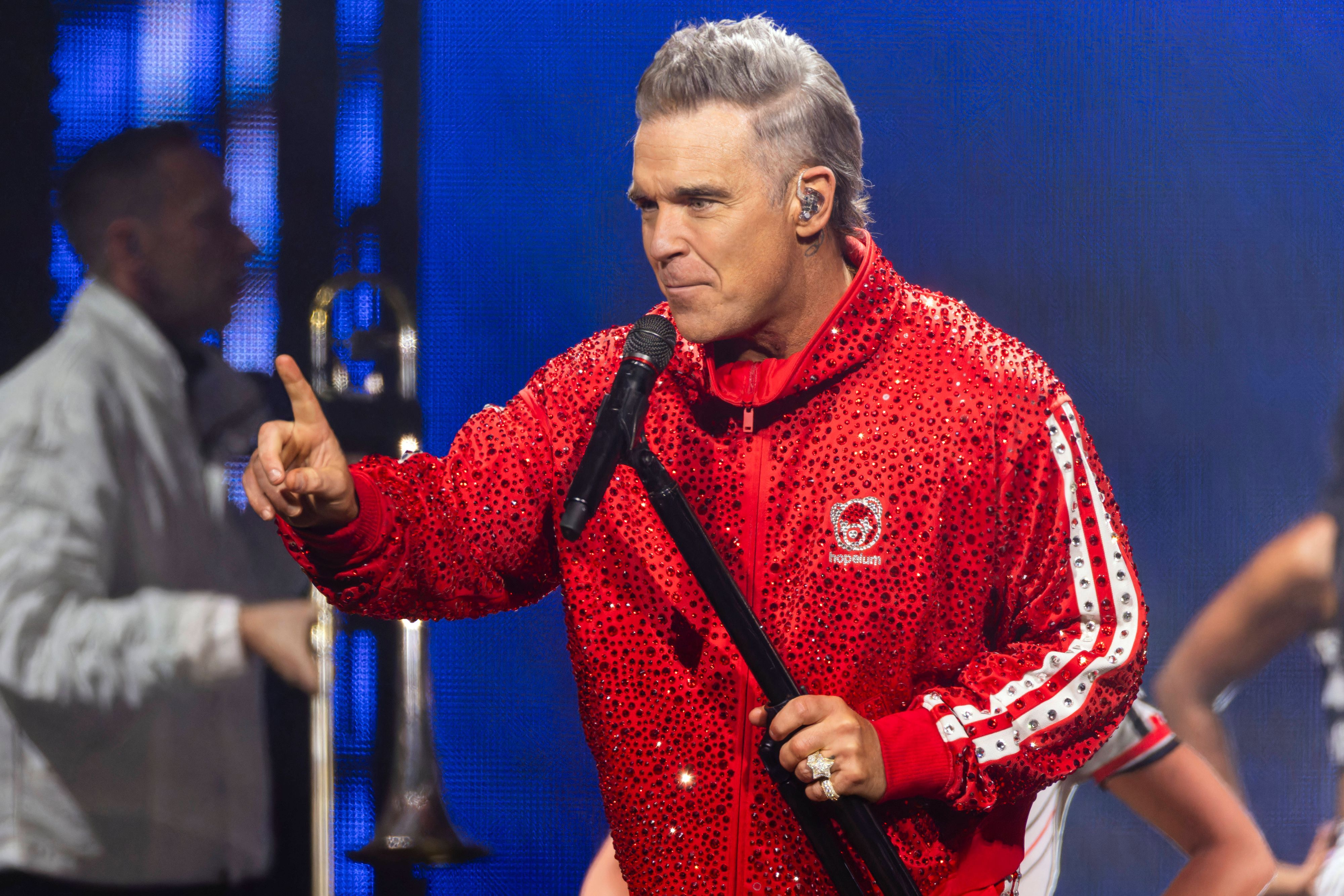 Robbie Williams steht beim Auftritt auf der Bühne.
