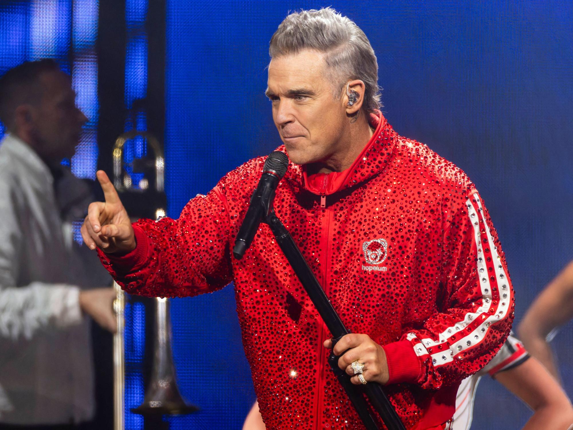 Robbie Williams steht beim Auftritt auf der Bühne.