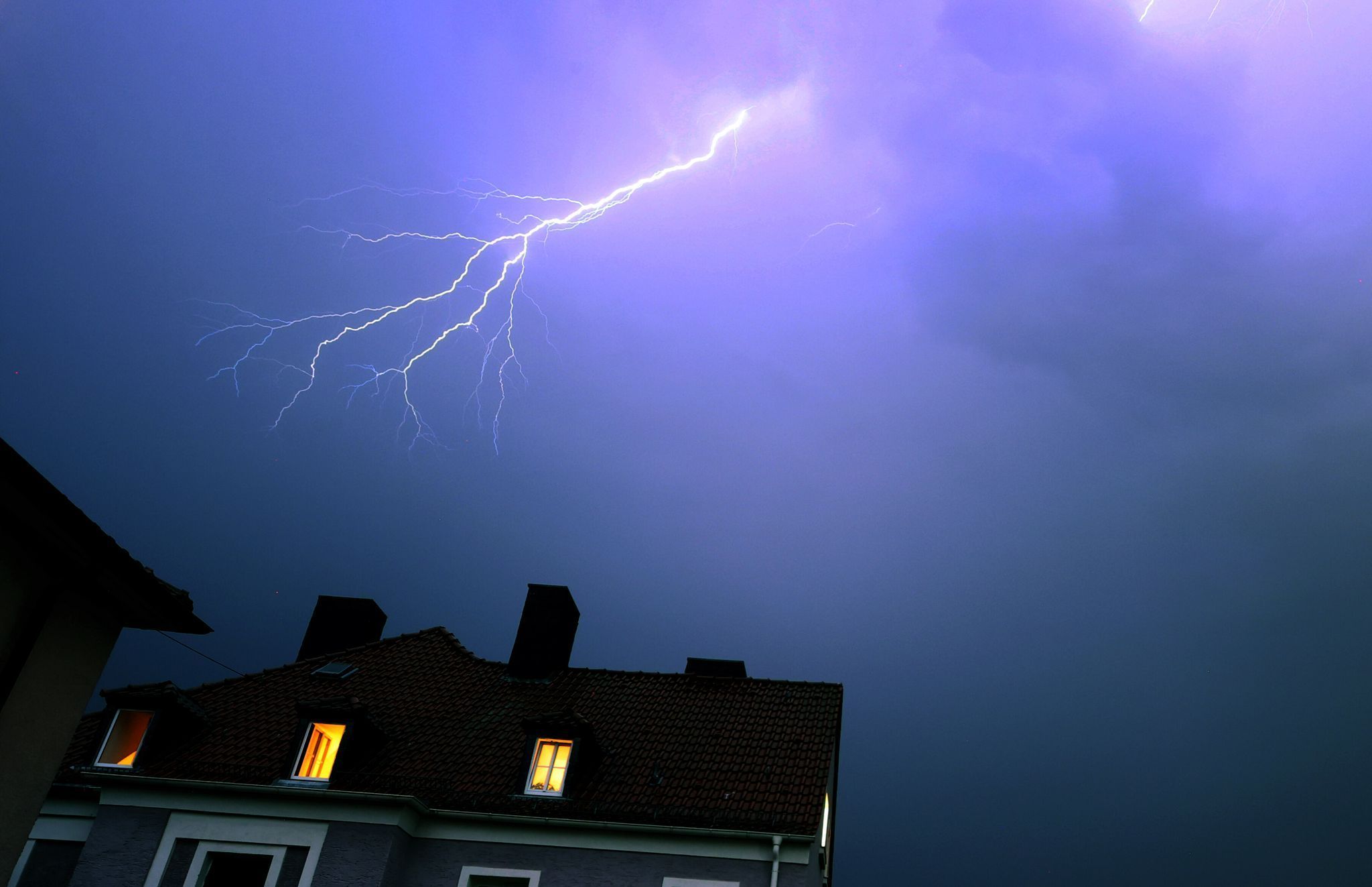 Blitze über einem Wohnhaus während eines Gewitters