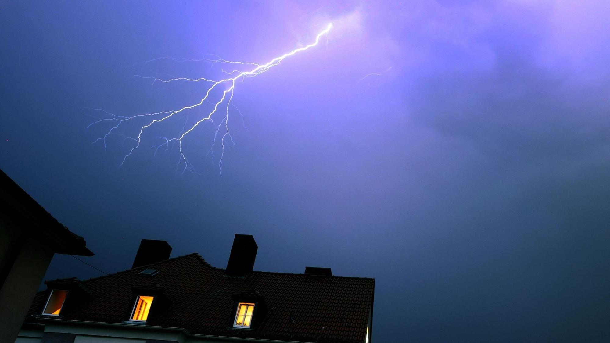 Blitze über einem Wohnhaus während eines Gewitters
