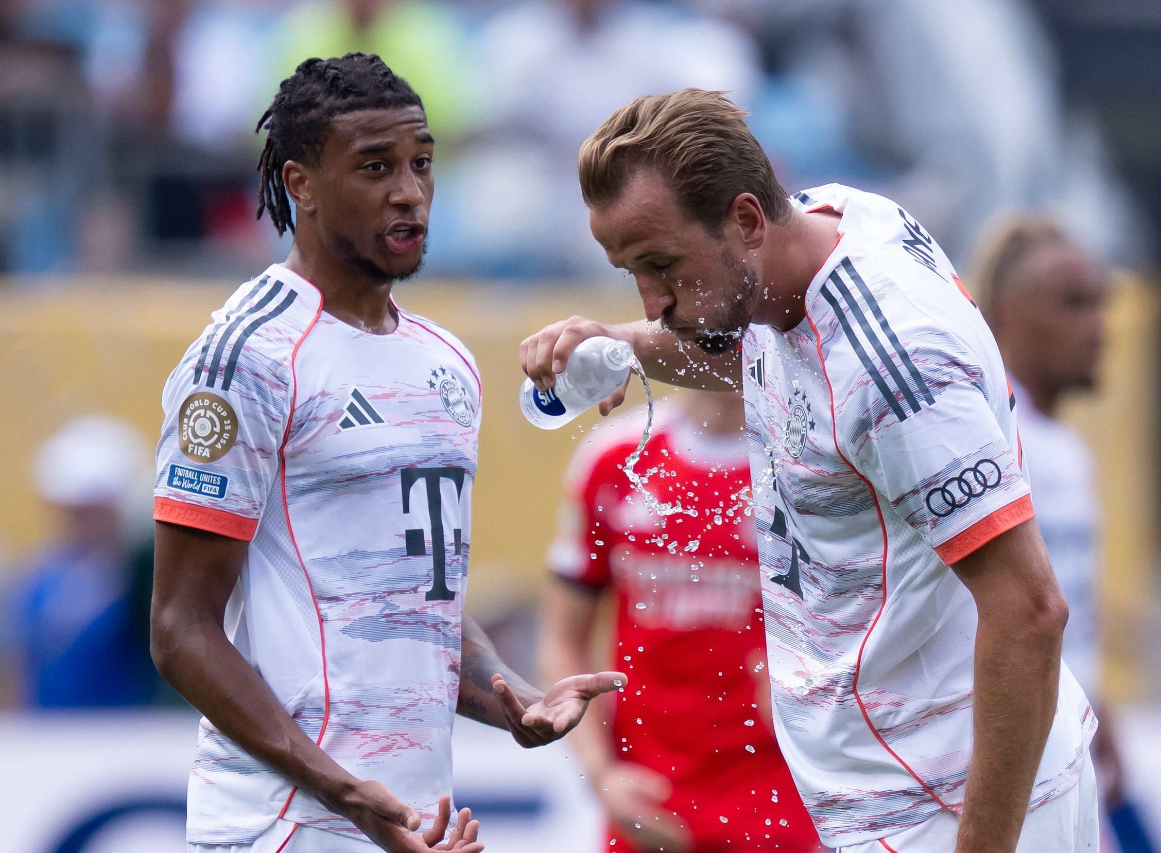 Michael Olise (l.) und Harry Kane stehen bei einer Trinkpause zusammen.