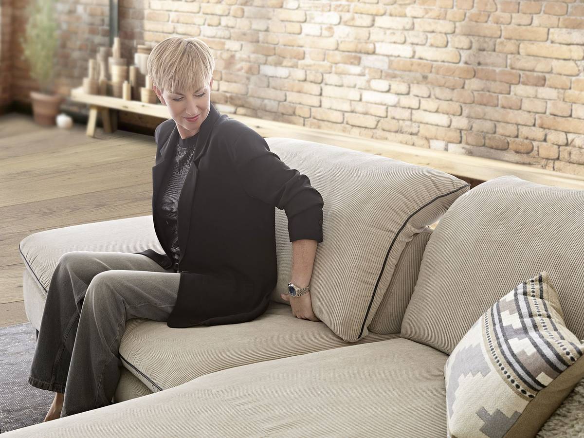 Eine Frau beim Probesitzen auf einem neuen Sofa