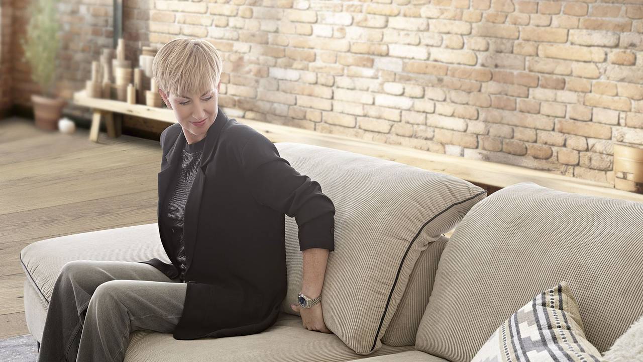 Eine Frau beim Probesitzen auf einem neuen Sofa