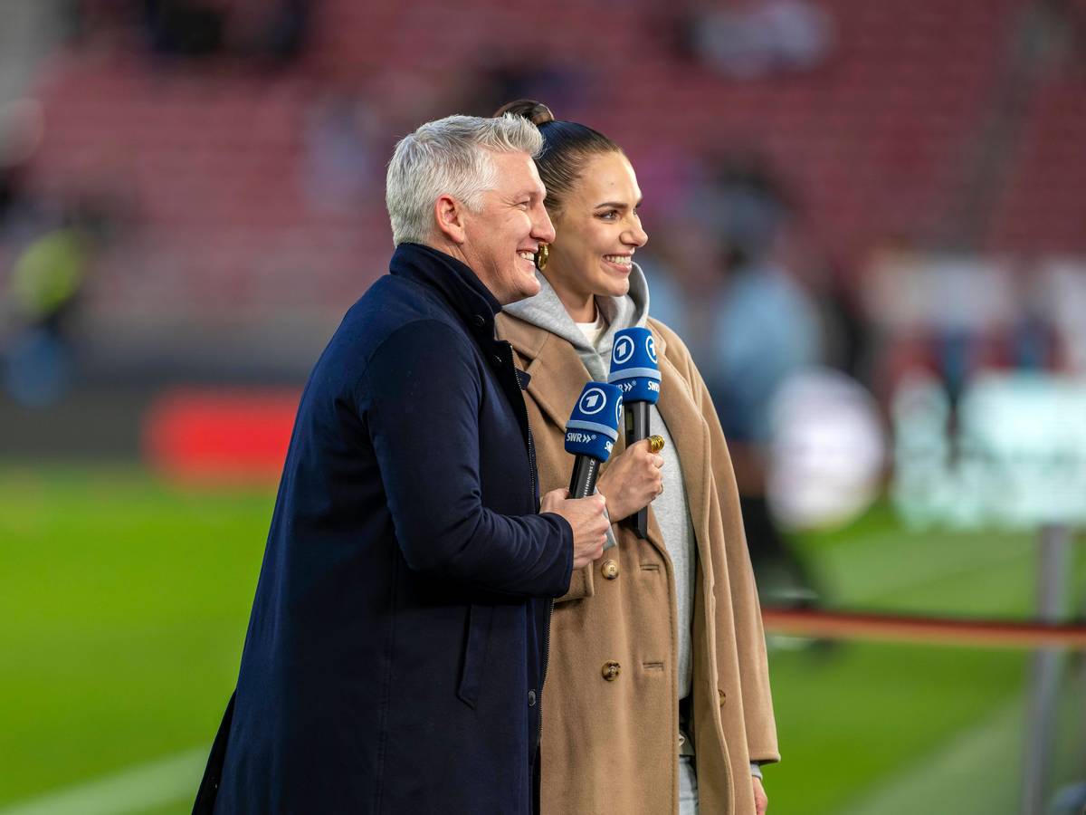 Bastian Schweinsteiger und Esther Sedlaczek mit Mikrofonen lächelnd.