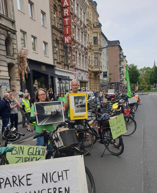 Bei einer Greenpeace-Aktion drehten Teilnehmende am Montag (8. Juni 2026) den Spieß um und blockierten auf der Bonner Straße mit Fahrrädern die Fahrbahn mit Entschuldigungen, wie „Komme gleich wieder...“.
