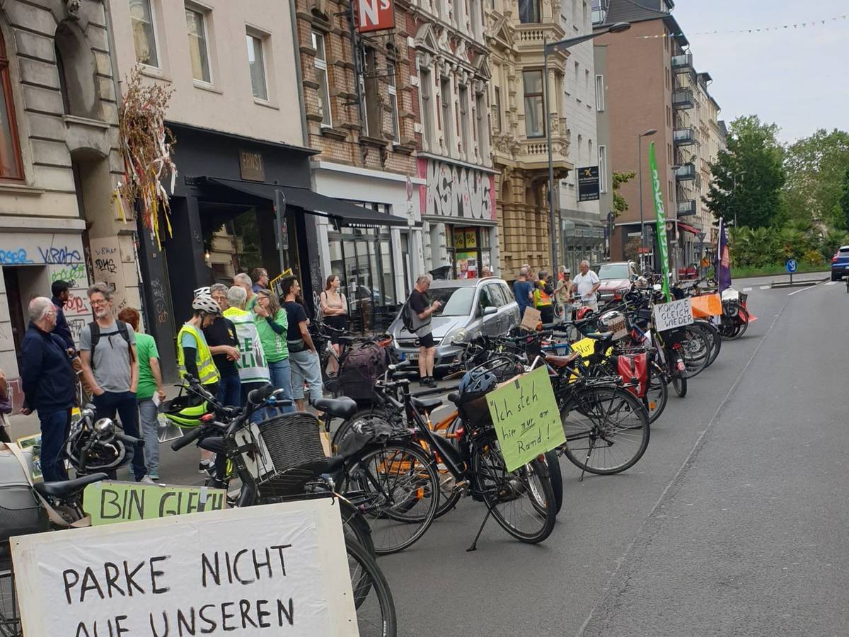 Fahrräder stehen auf der Fahrbahn, an ihnen hängen Plakate u. a. mit der Aufschrift: Parke nicht auf unseren Wegen!