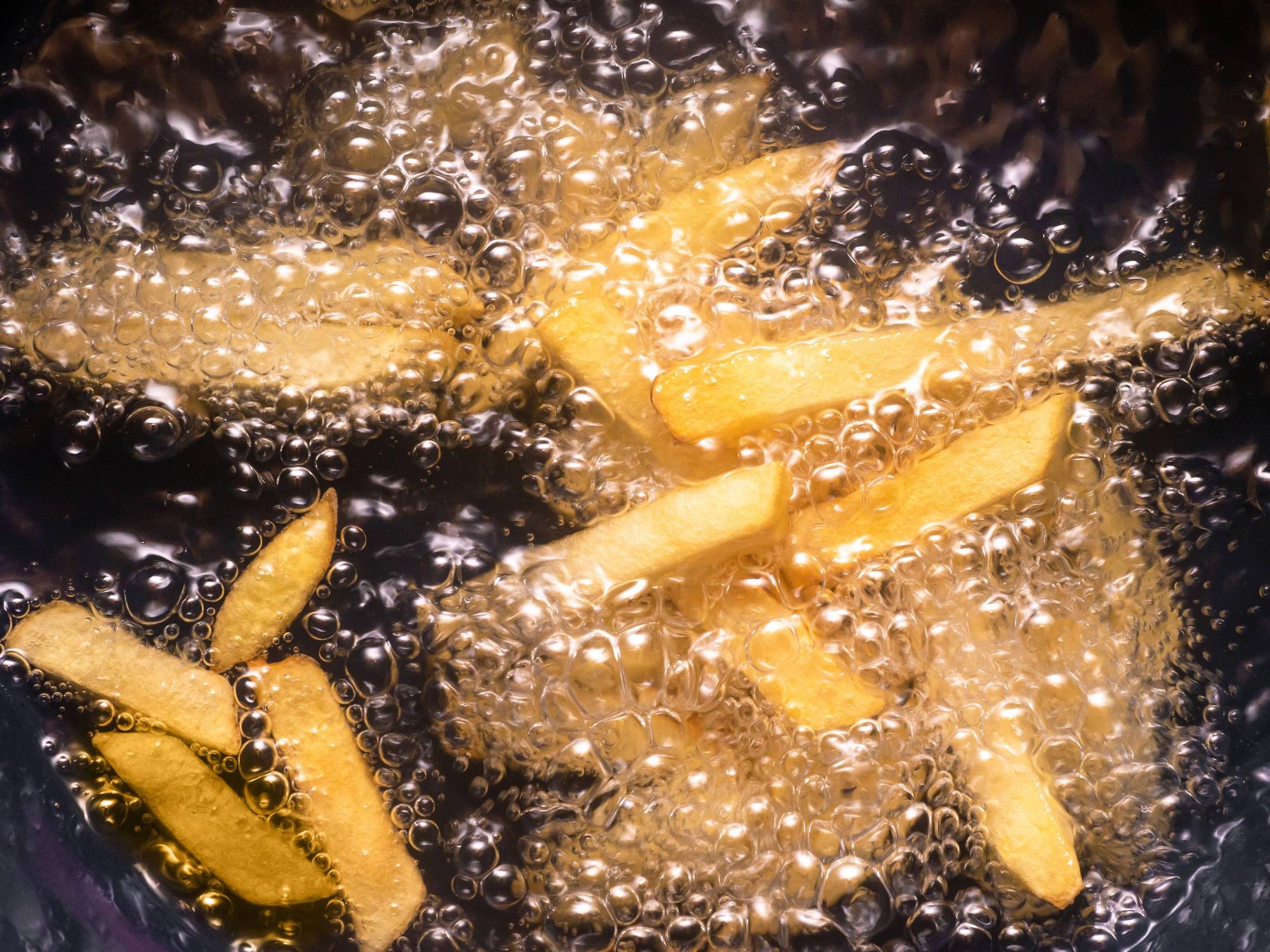 Pommes frites werden in heißem Öl frittiert.