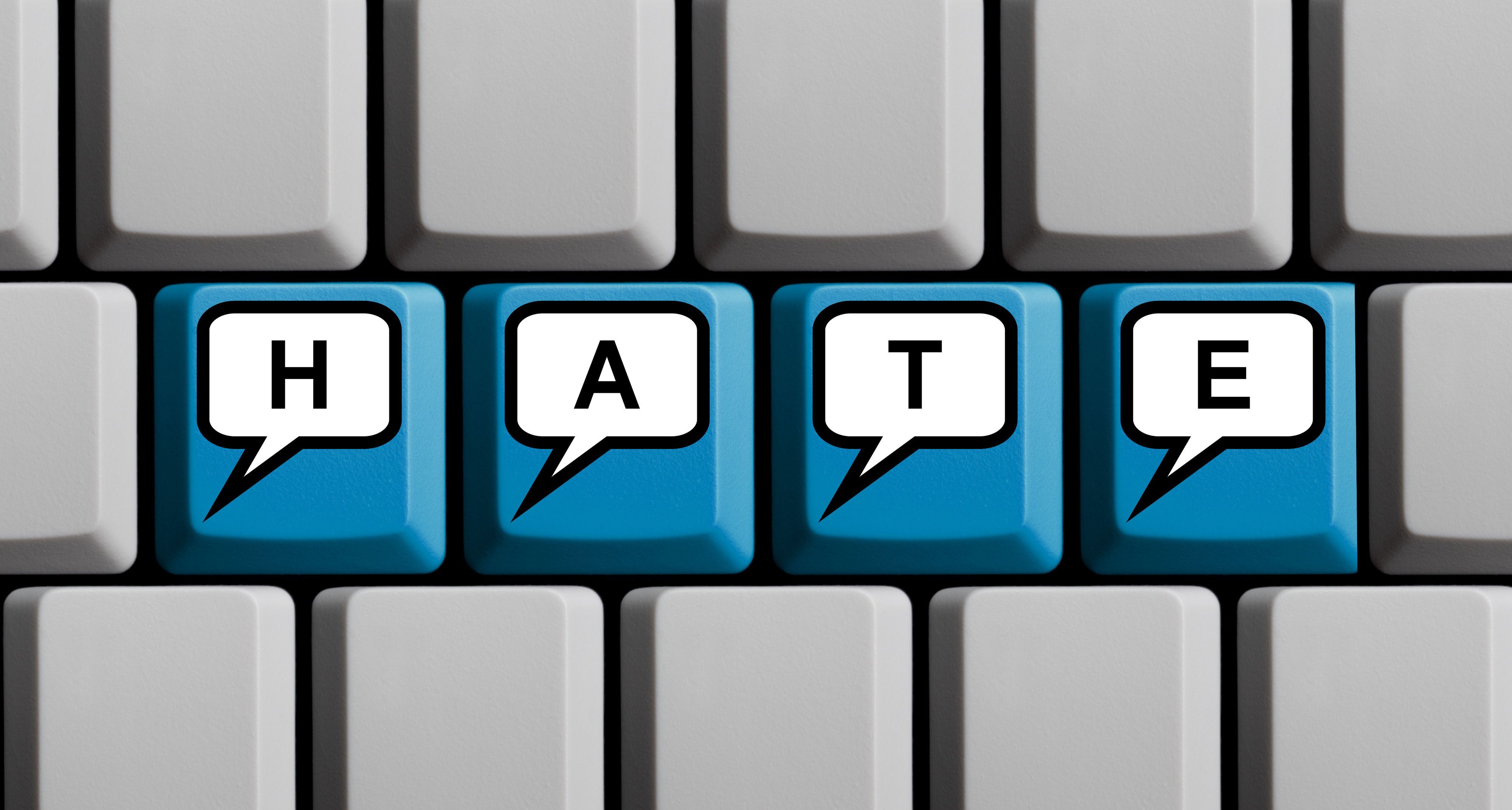 Blaue Tastatur mit Wort HATE in Sprechblasen