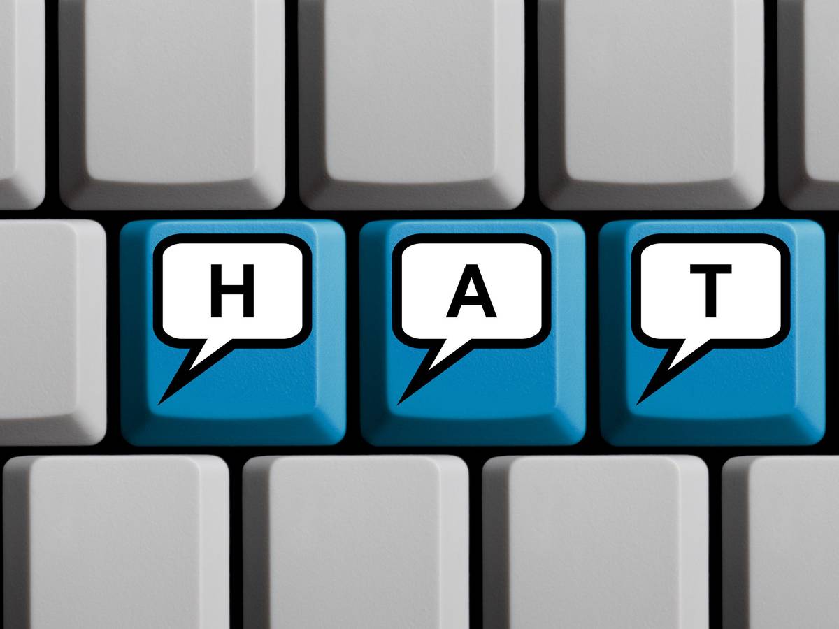 Blaue Tastatur mit Wort HATE in Sprechblasen