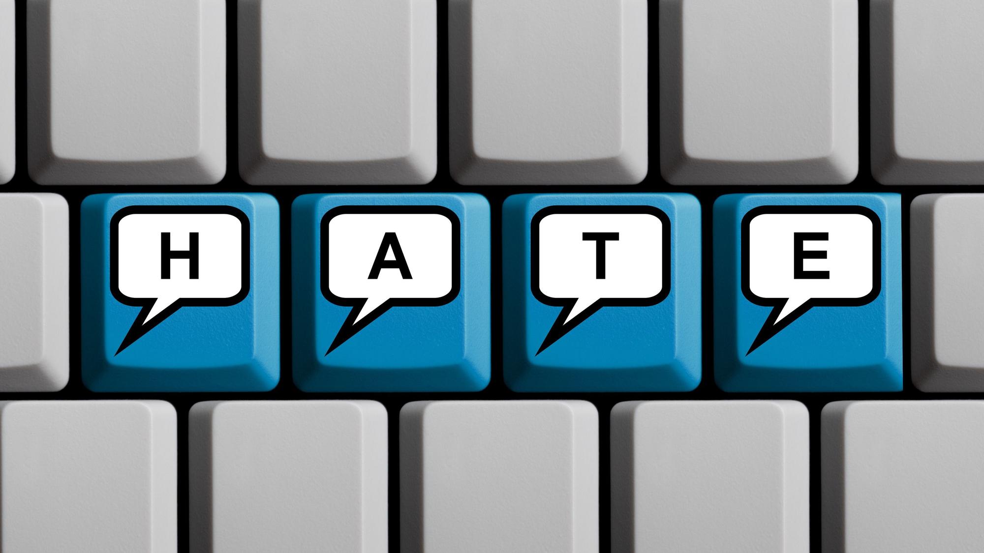 Blaue Tastatur mit Wort HATE in Sprechblasen