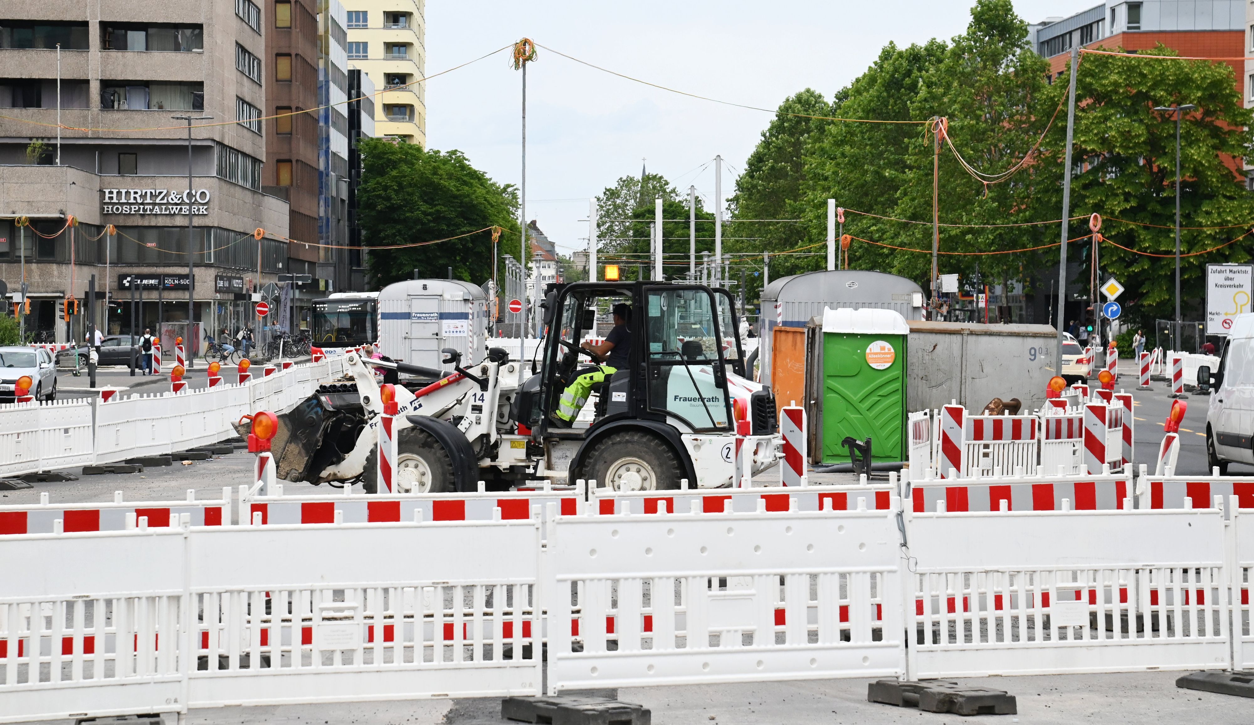 Bauzäune und Baumaschine stehen auf einer Straße.