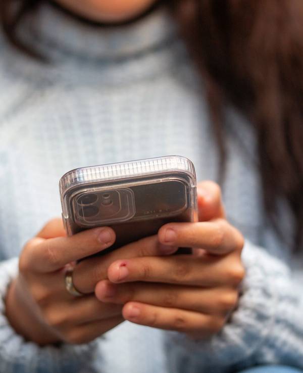 Eine junge Frau hält ein Smartphone in den Händen