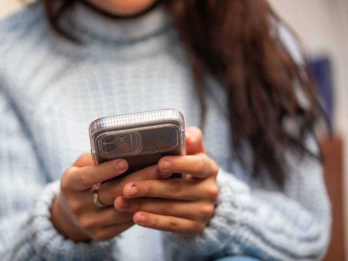 Eine junge Frau hält ein Smartphone in den Händen