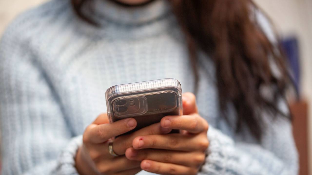 Eine junge Frau hält ein Smartphone in den Händen