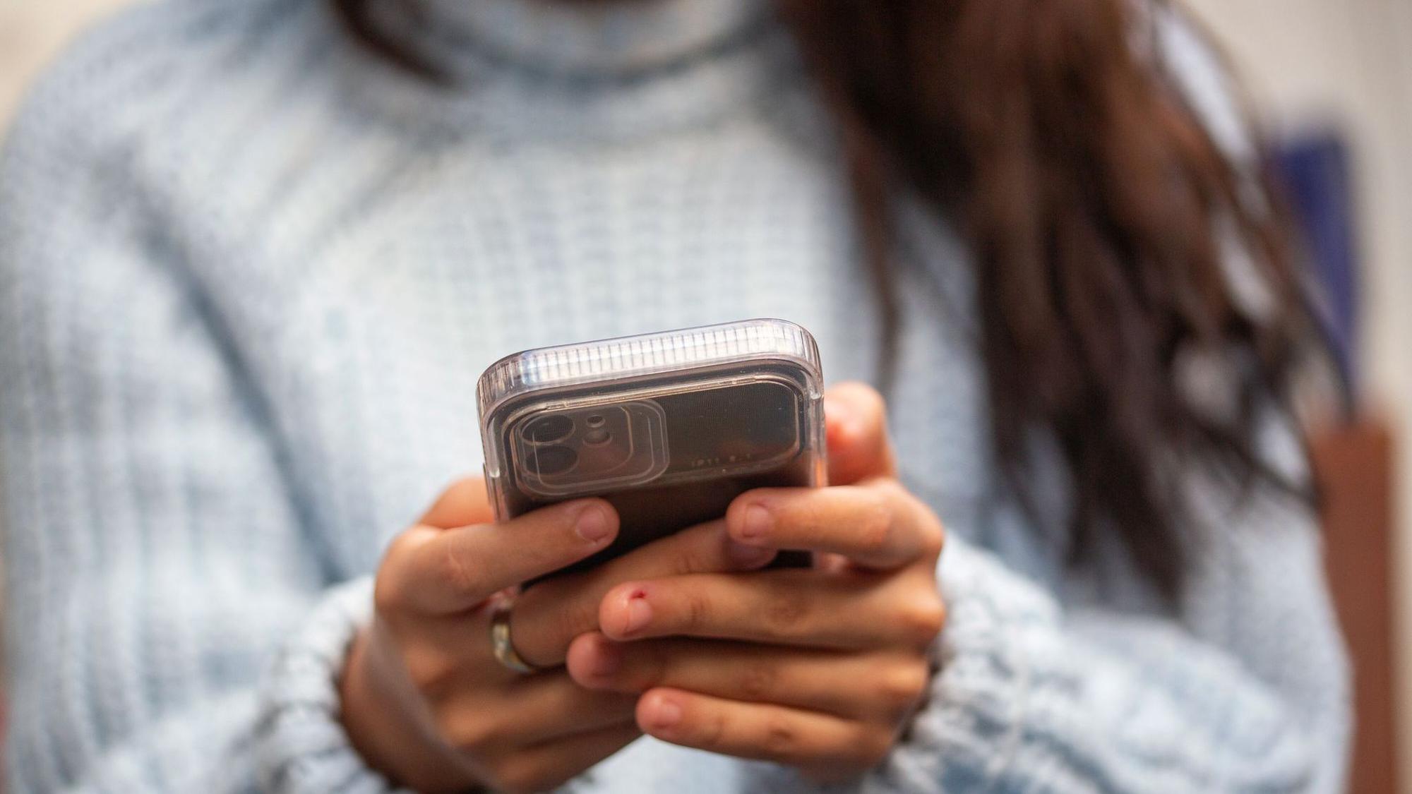 Eine junge Frau hält ein Smartphone in den Händen