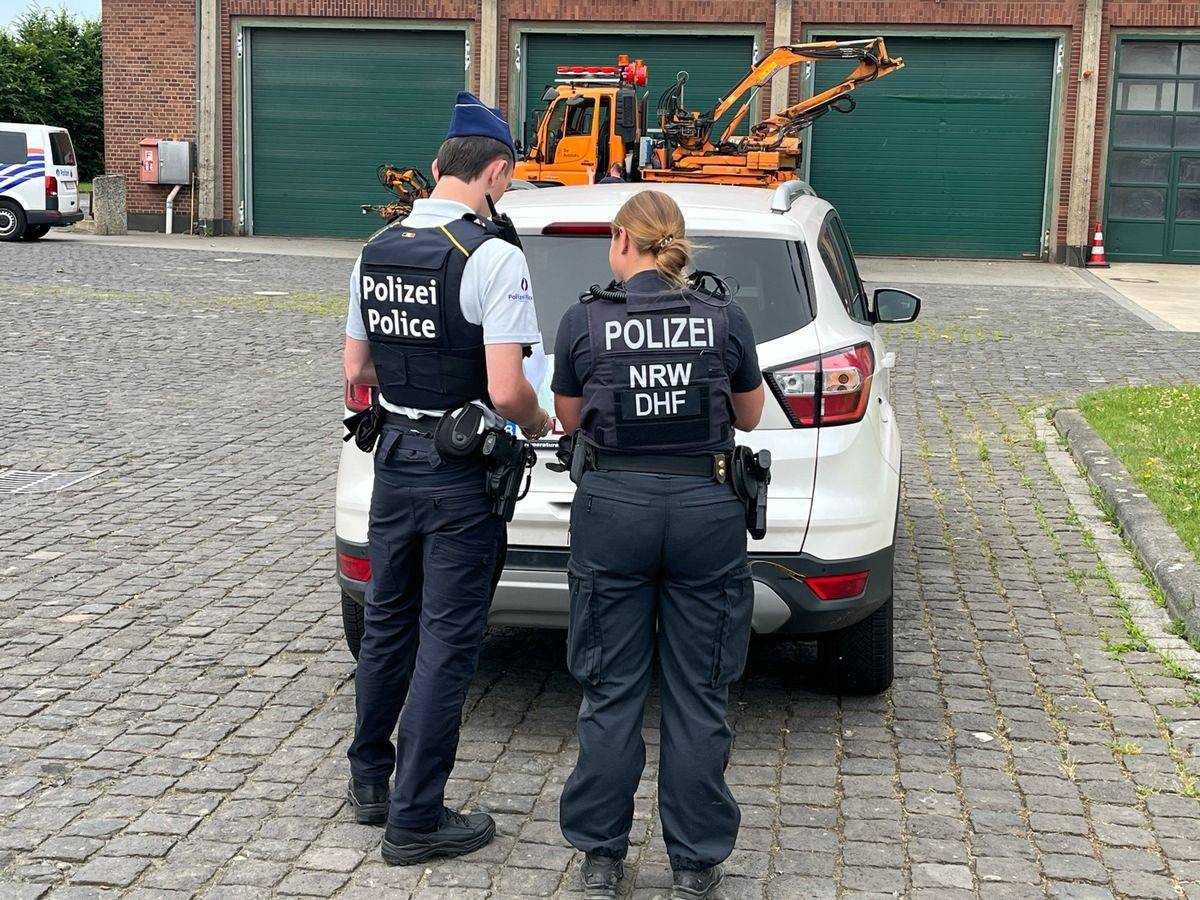 Mehrere Polizisten und Polizistinnen führen eine Fahrzeugkontrolle auf einer Straße durch.