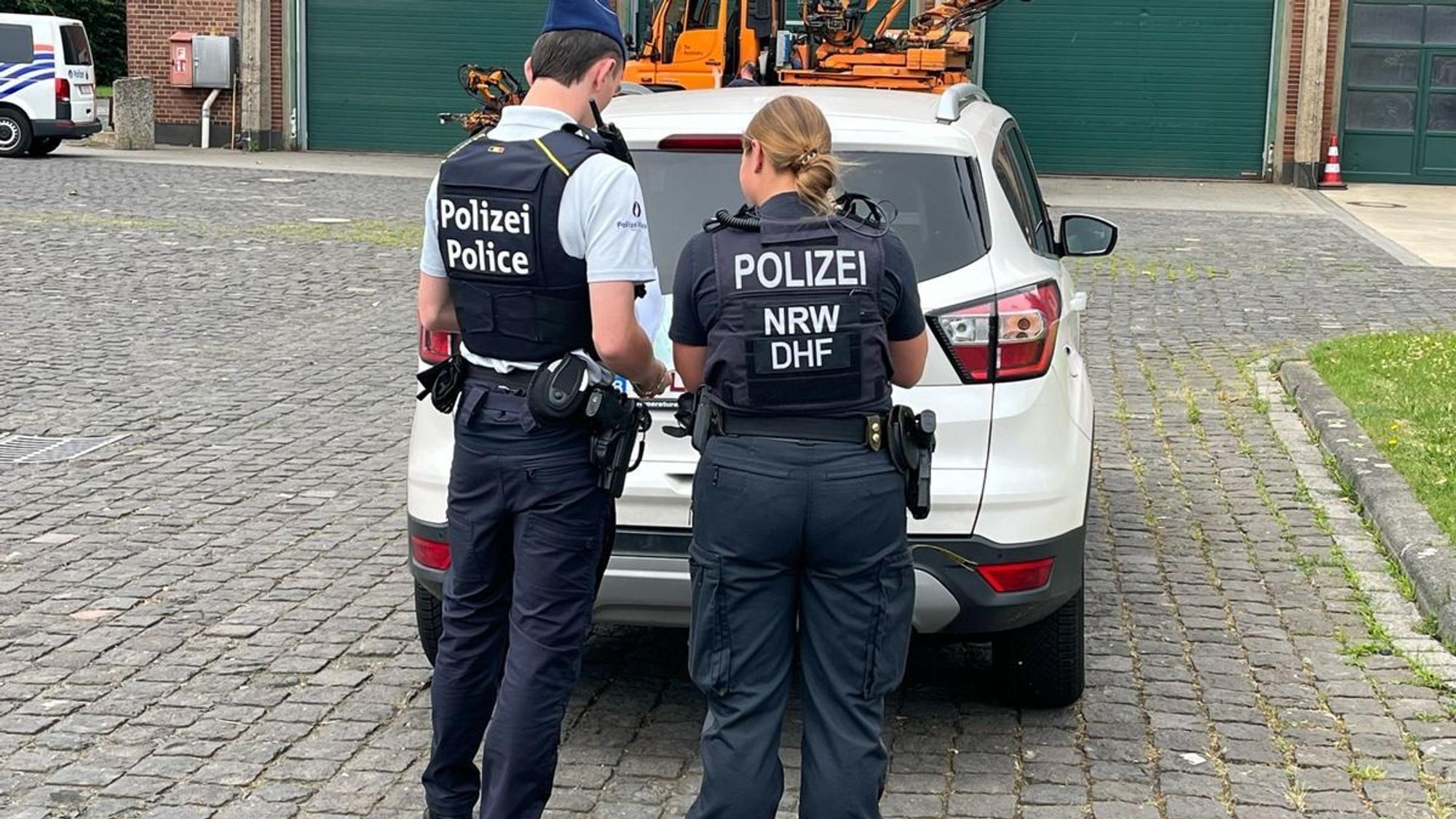 Mehrere Polizisten und Polizistinnen führen eine Fahrzeugkontrolle auf einer Straße durch.