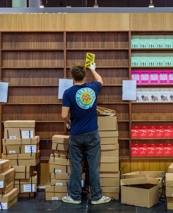 Ein junger Mann räumt Bücher in ein Regal ein