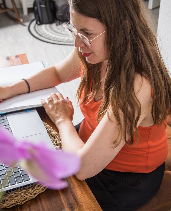 Eine Frau macht sich Notizen neben dem Laptop