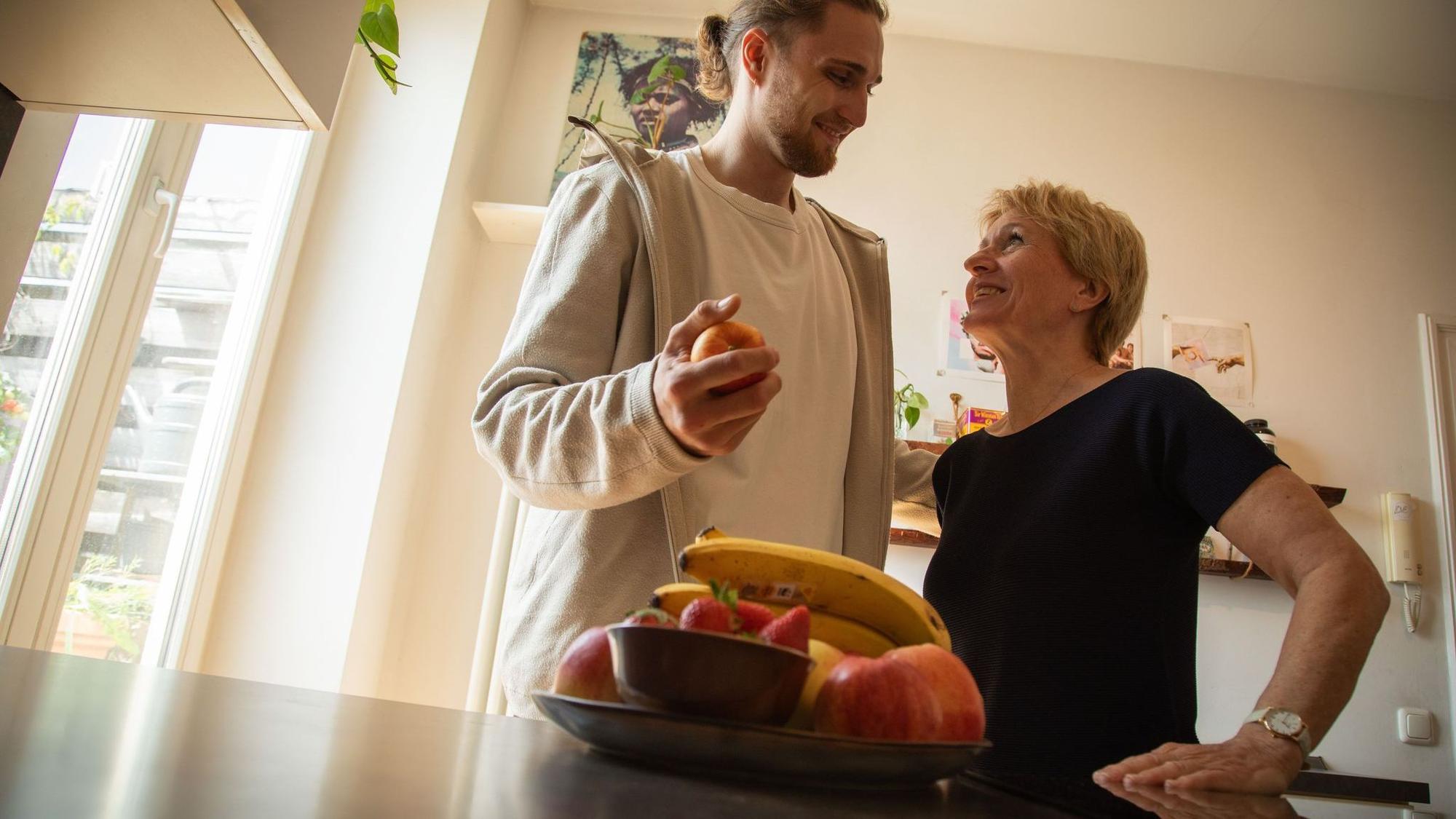 Ein junger Mann hilft einer älteren Frau in der Küche