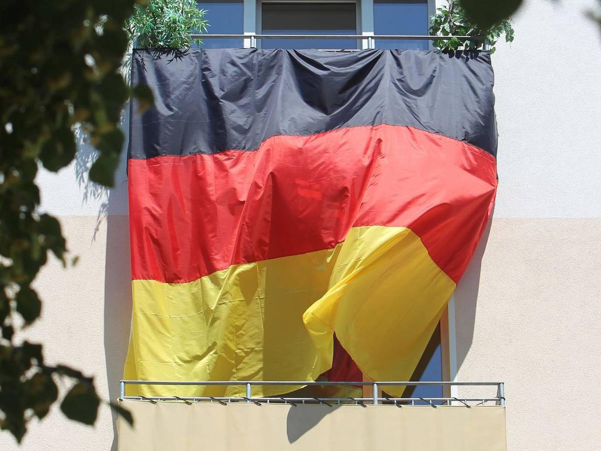 Eine Deutschlandflagge hängt von Balkon zu Balkon