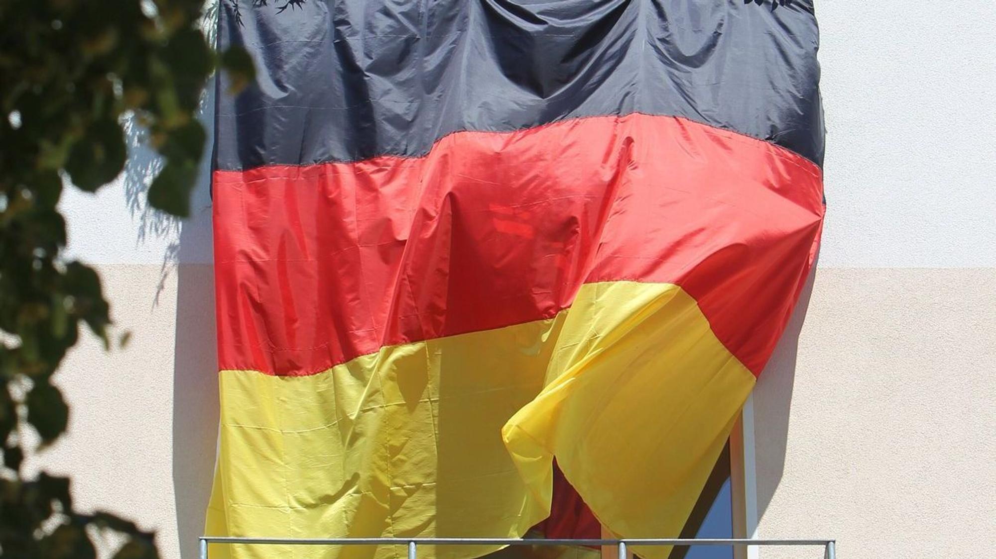 Eine Deutschlandflagge hängt von Balkon zu Balkon
