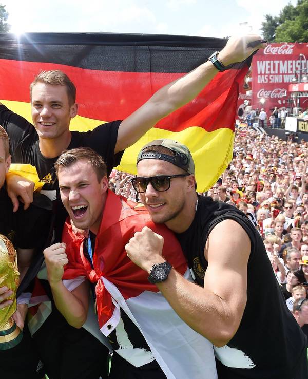 Fünf Fußballer jubeln, während im Hintergrund Fan-Massen stehen.