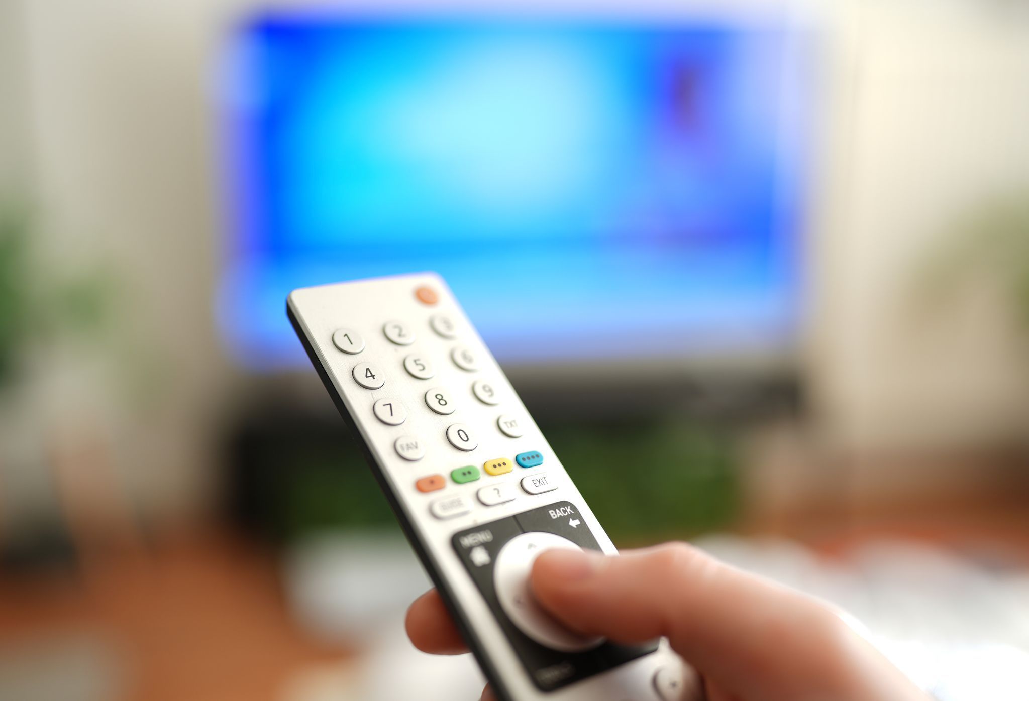 Ein Mann drückt einen Knopf auf einer TV-Fernbedienung