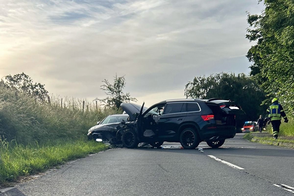 Ein verunfalltes Auto steht am Straßenrand, im Hintergrund ein Polizeiwagen.