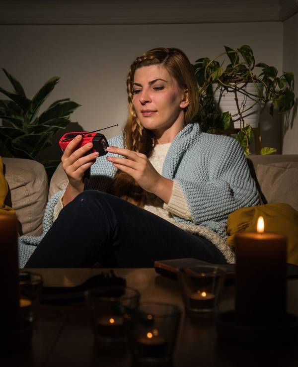 Eine Frau mit Kerzen während eines Stromausfalls auf dem Sofa