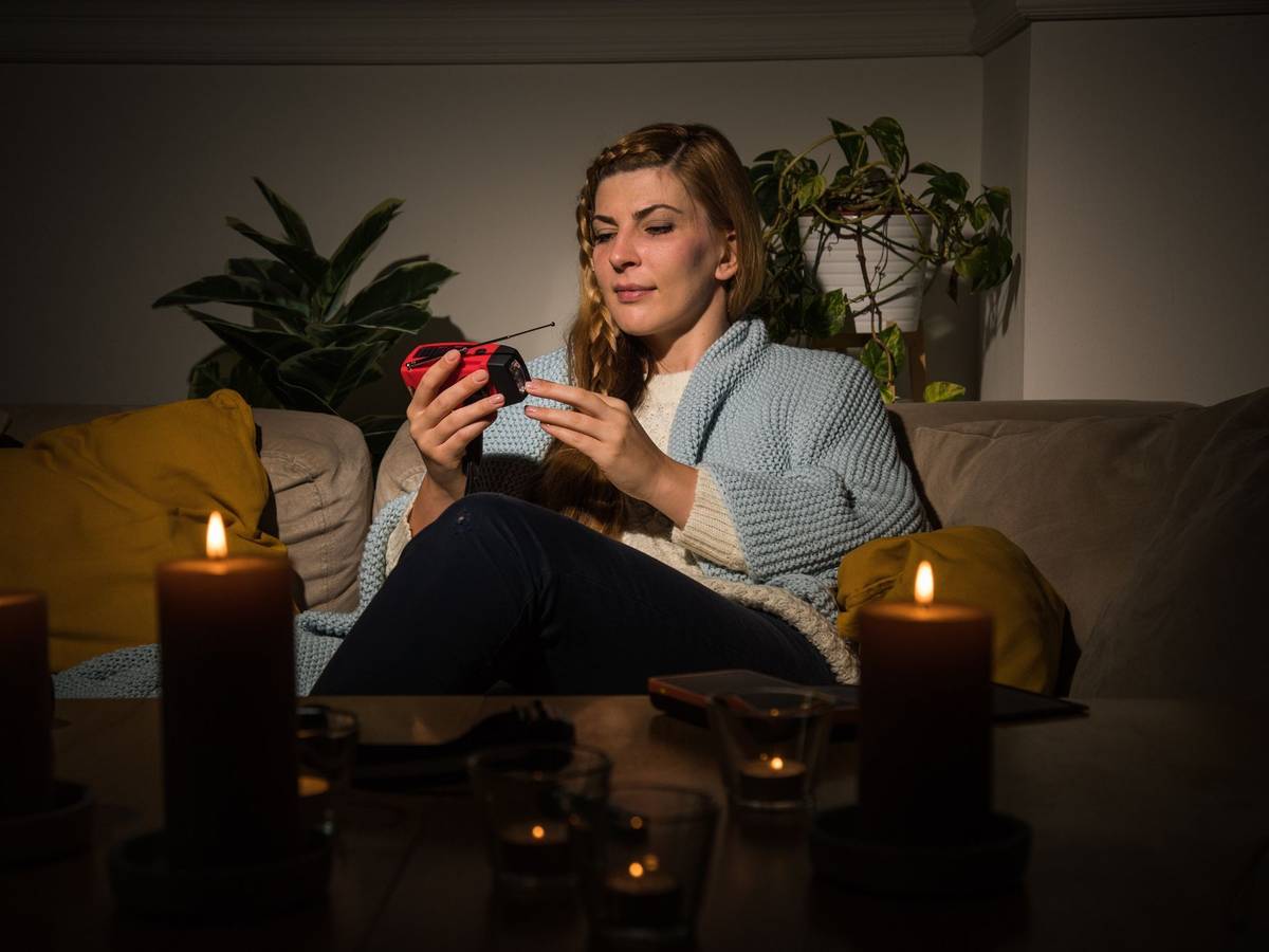 Eine Frau mit Kerzen während eines Stromausfalls auf dem Sofa