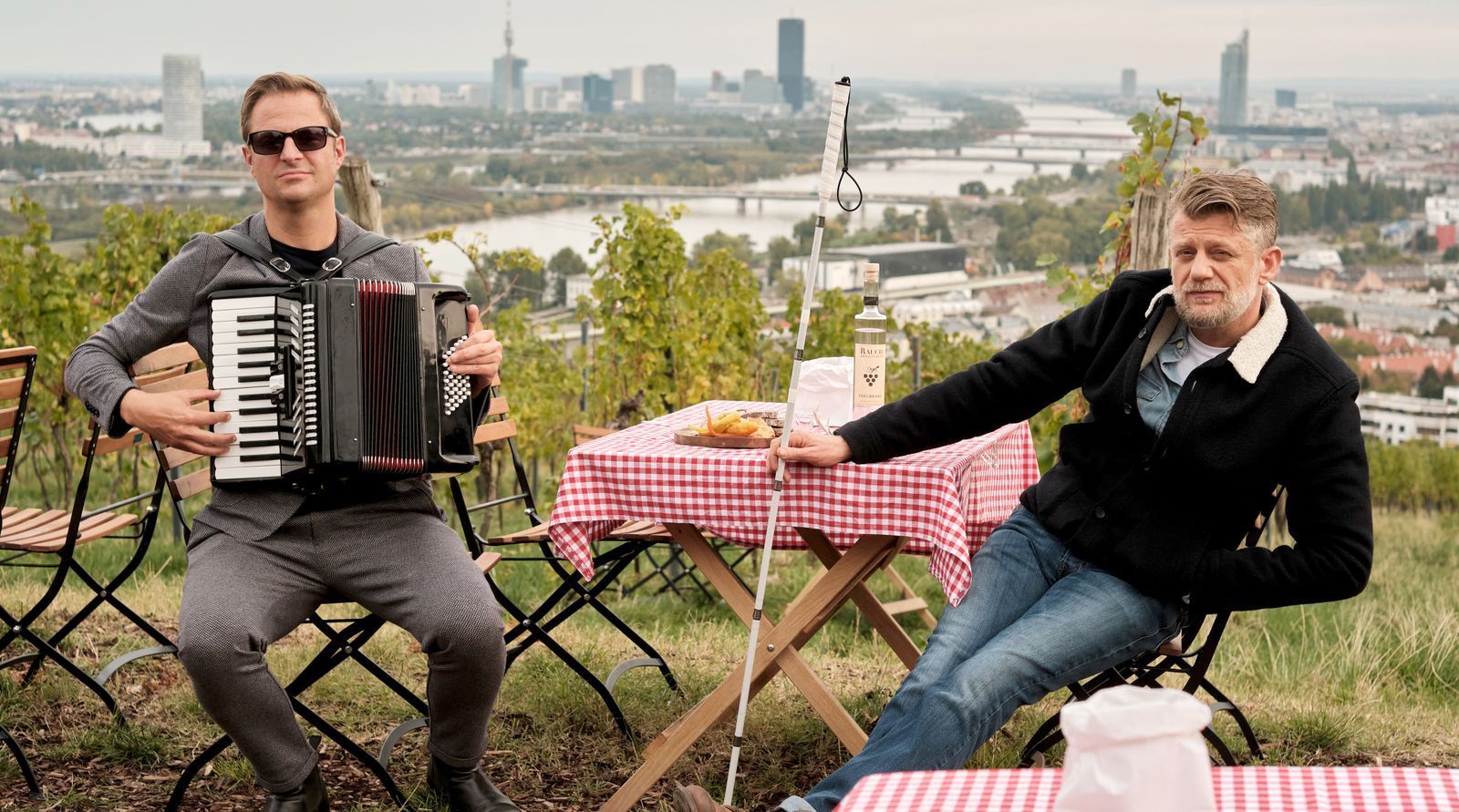 Lebenswertes Wien: Sonderermittler Haller (Philipp Hochmair, links) und sein Partner Niko (Andreas Guenther) lassen es sich im Weinberg oberhalb Wiens beim Heurigen gut gehen. (Bild: ARD Degeto/Tivoli Film/Philipp Brozsek)