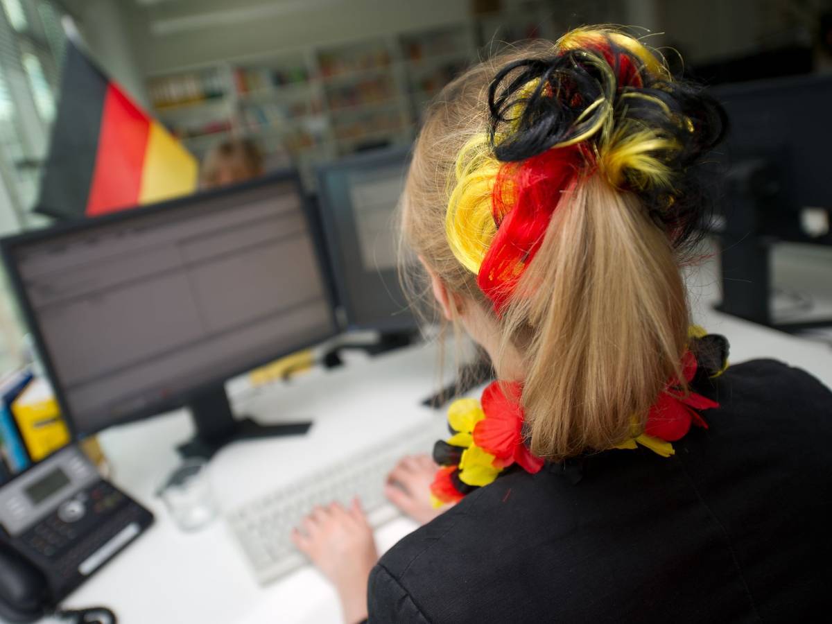Eine Frau sitzt mit WM-Deko vor einem Computer