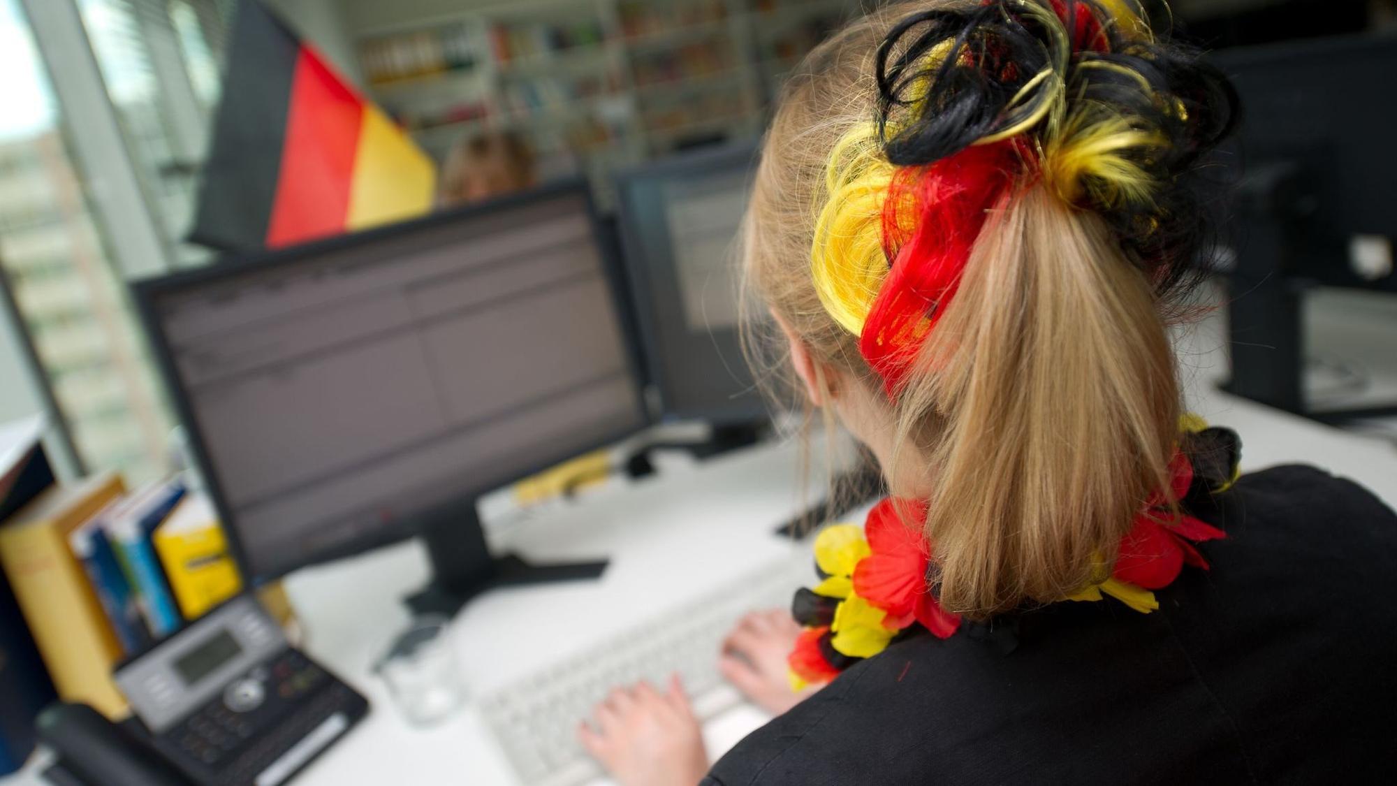 Eine Frau sitzt mit WM-Deko vor einem Computer
