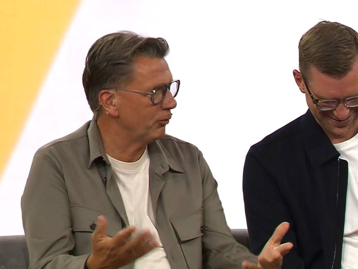 Thorsten Kinhöfer sitzt neben Per Mertesacker und gestikuliert.
