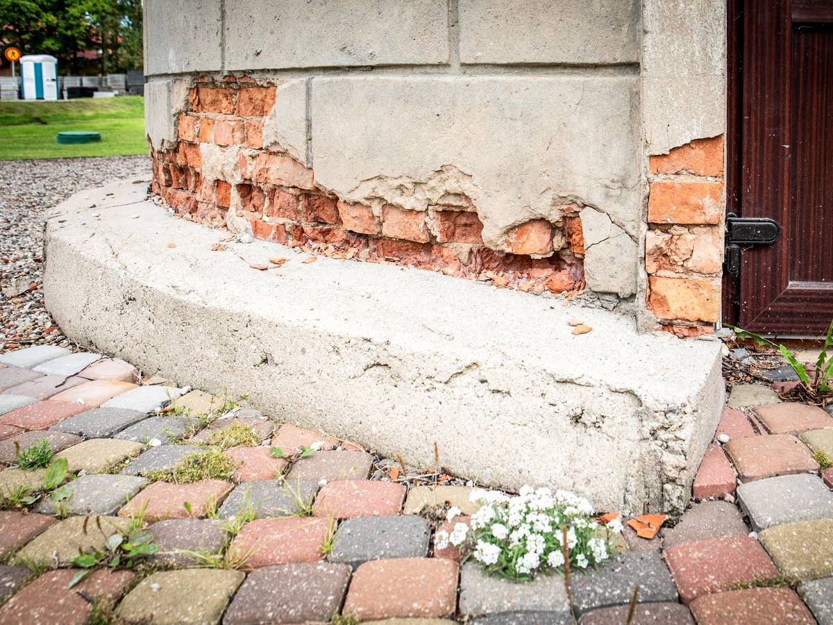 Beschädigtes Gebäudefundament mit Pflastersteinen und Pflanzen
