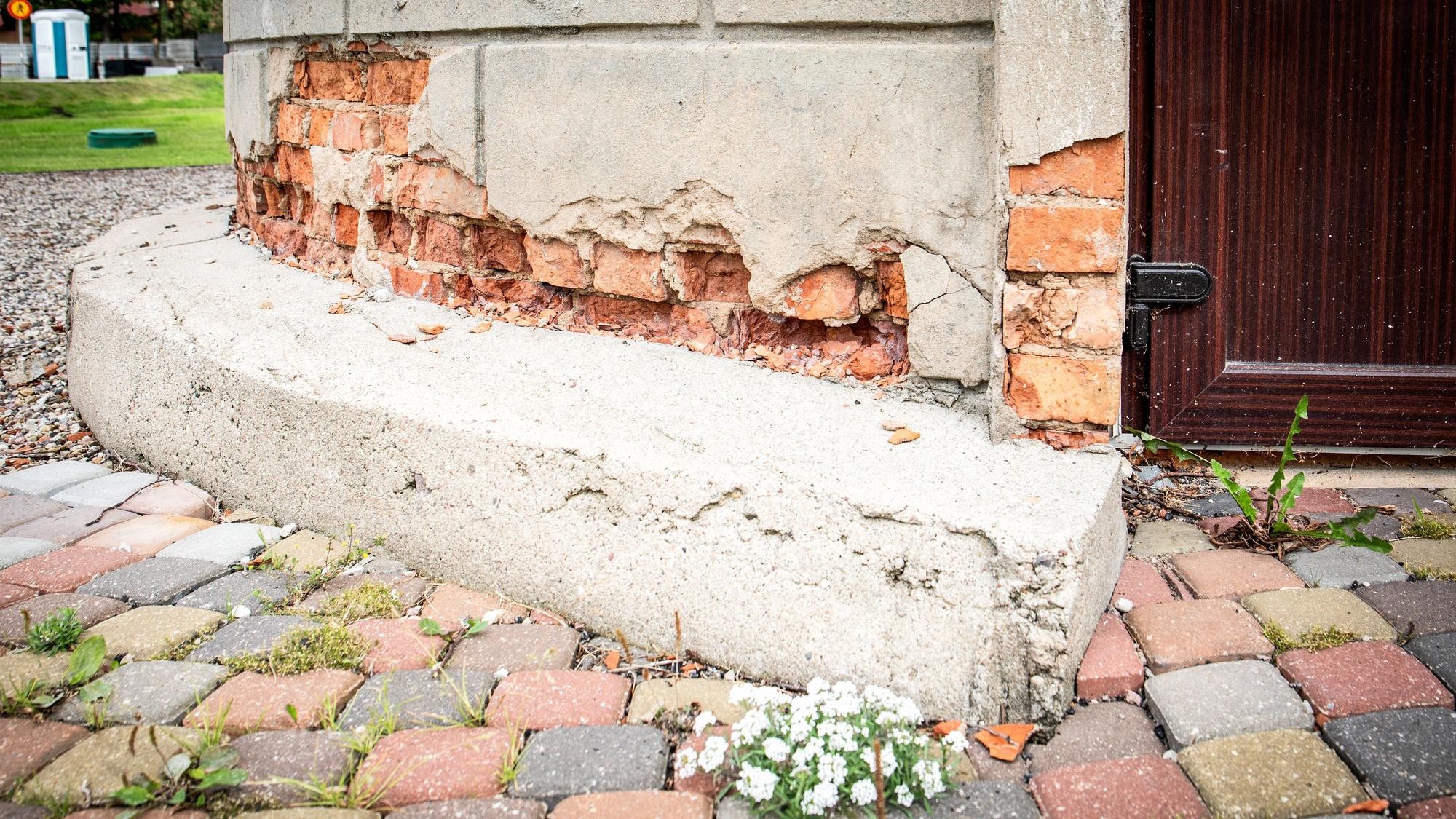 Beschädigtes Gebäudefundament mit Pflastersteinen und Pflanzen