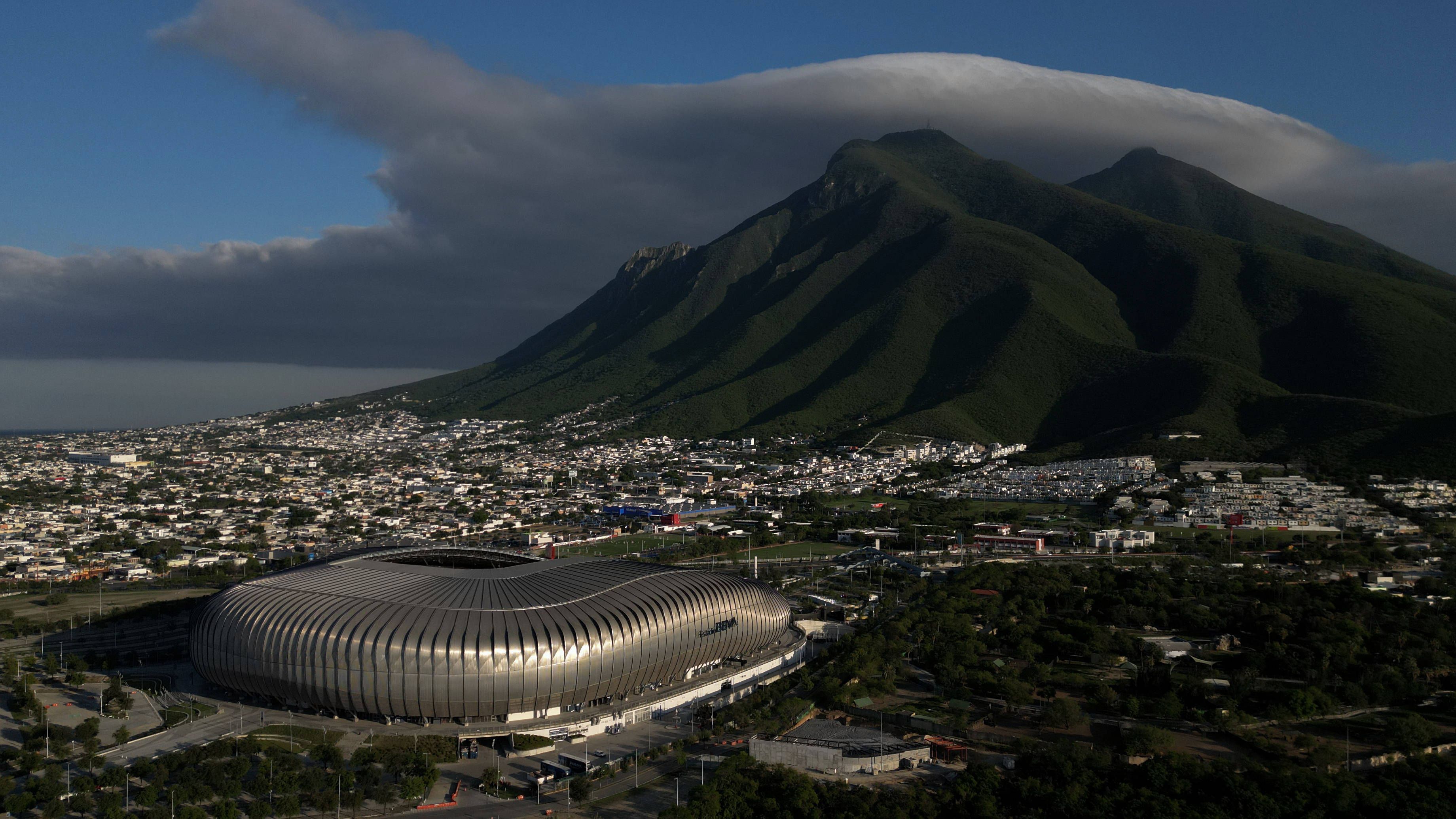 Ein futuristisches Stadion mit Blick auf eine Gebirgskette und eine Großstadt