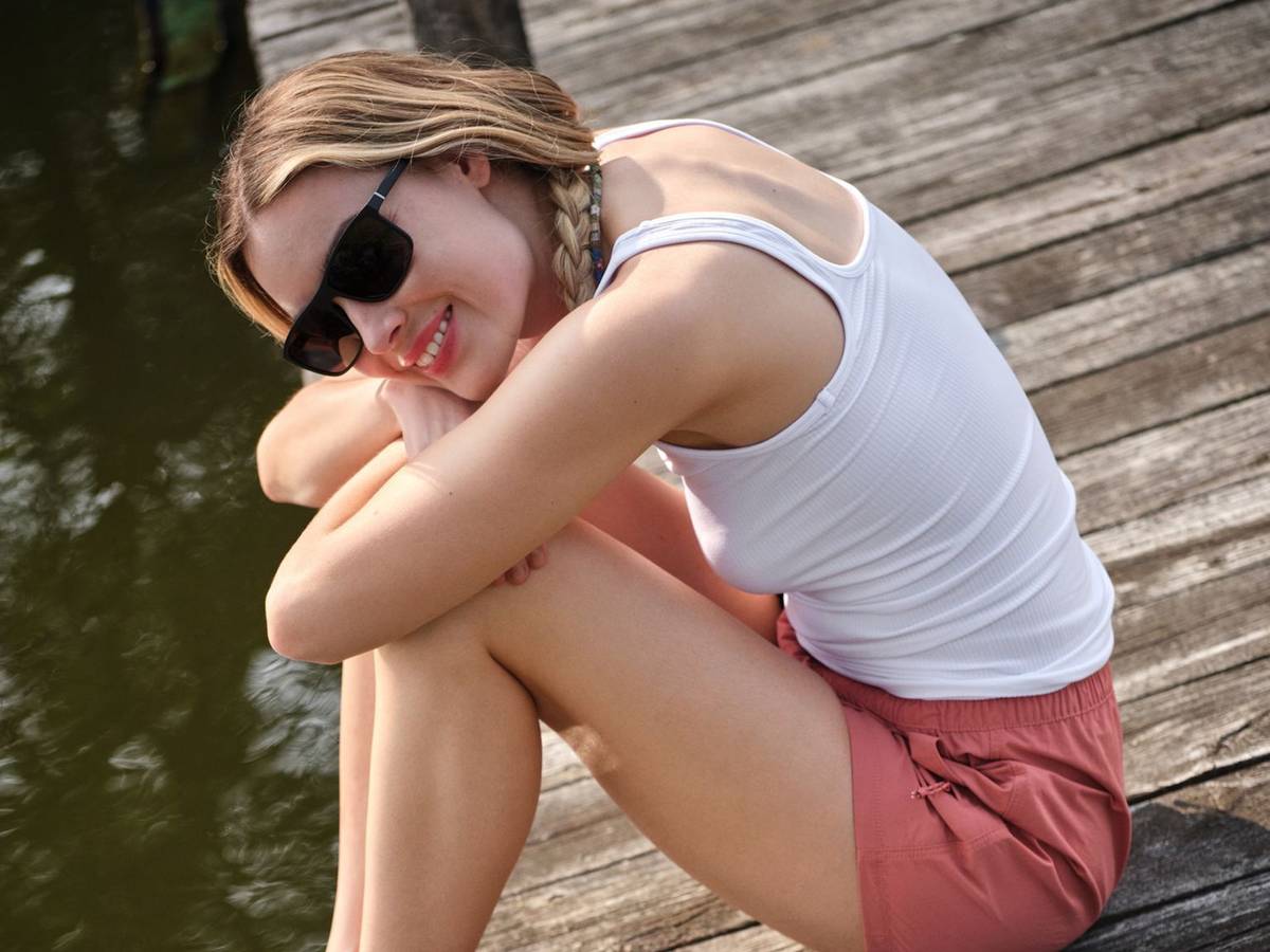 Ein Frau sitzt auf einem Steg neben Sandalen