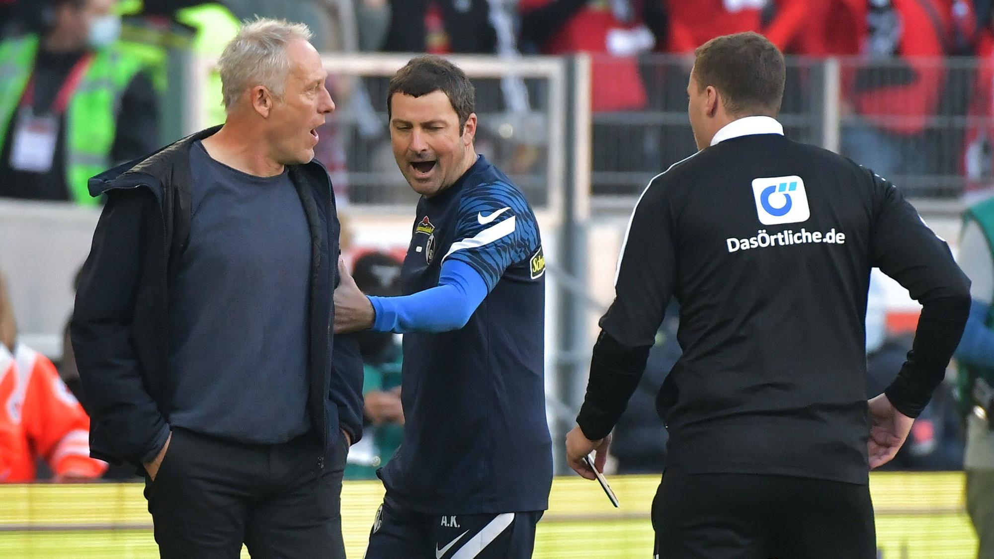 Der wütende Christian Streich wird von seinem Co-Trainer zurückgehalten.